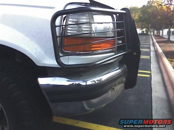 White Ford truck front corner with a black bull bar over the headlight and chrome bumper