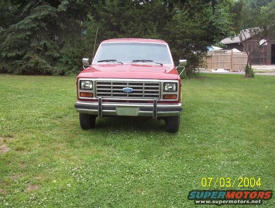Red Ford Bronco parked on grass, front view. Chrome grille and bumper. Date stamp 07/03/2004