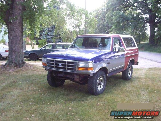 Ford Bronco with blue hood, silver sides, and red rear quarter panels parked on grass
