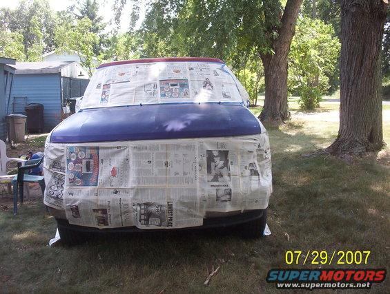 van covered in newspaper for painting, front view