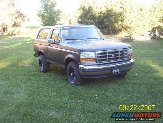 Gray Ford Bronco parked on grass, front-right view. Grille has horizontal bars and a Ford logo