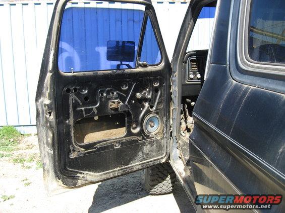 Interior of black vehicle with door open, showing exposed door panel and dashboard