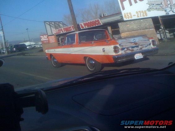 Orange and white car with chrome trim and hubcaps, seen from inside another vehicle