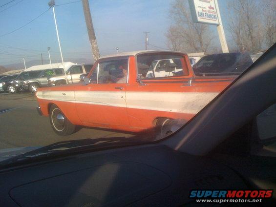 Orange and white pickup truck side view, parked at a dealership