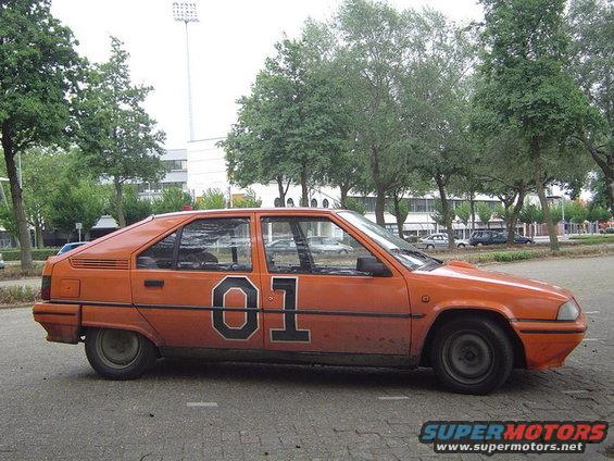 Orange hatchback with black number 01 on the door, parked on asphalt
