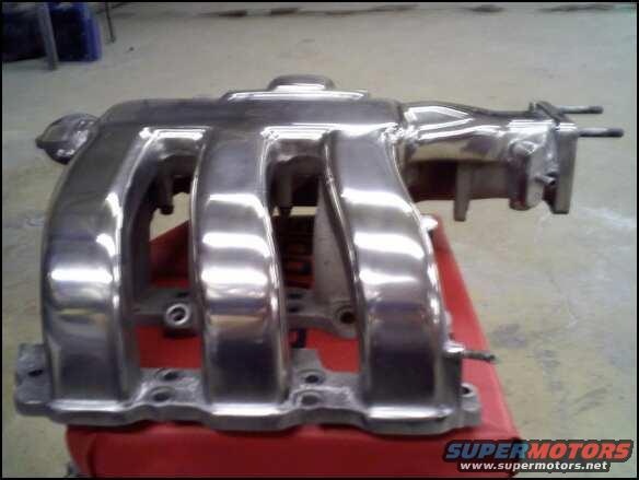 Polished intake manifold on a red surface