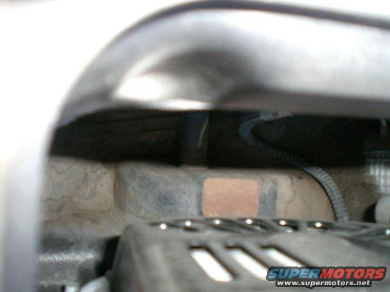Close-up of engine bay components, including a black ribbed hose and wiring harness