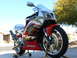 1978 Ford Bronco - A red and silver Honda sport motorcycle is displayed on stands outdoors under a clear blue sky.