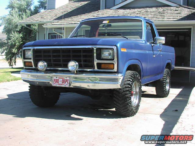 Blue 1981 Ford Bronco front view with off-road tires and 'FIRE DEPT' license plate