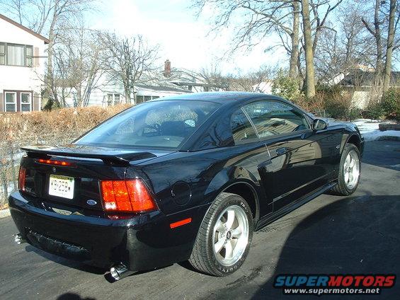 Black 2002 Ford Mustang coupe parked on driveway, rear 3/4 view