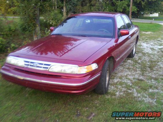 Red 1995 Ford Crown Victoria parked on grass with trees in the background