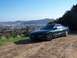 1996 Ford Probe - A green coupe is parked on a dirt road with a city in the background.