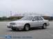 2001 Ford Crown Victoria - A silver 2001 Ford Crown Victoria sedan is parked in an empty lot with a stadium visible behind it.