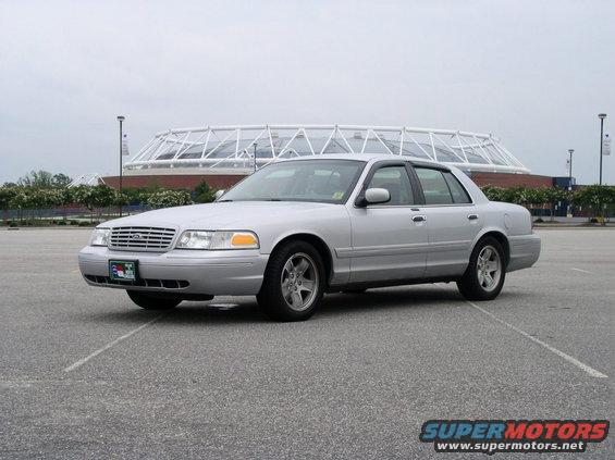 Silver 2001 Ford Crown Victoria parked in a lot with a stadium in the background