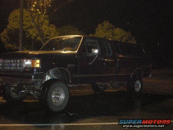 Black extended cab pickup truck, side view. Lifted suspension
