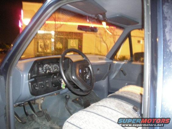 Truck interior with gray dashboard, steering wheel, and striped seat. "SUPERMOTORS" text visible