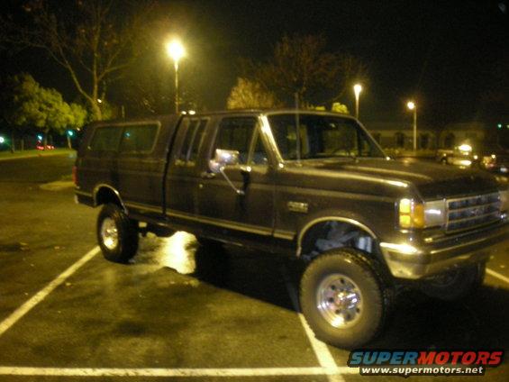 Dark-colored Ford F-Series truck with a camper shell, parked at night