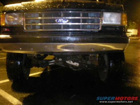 Black Ford Bronco front grille with chrome bumper and headlights. Wet surface