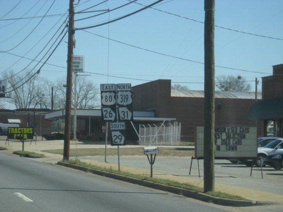 Roadside scene with highway signs, utility poles, and buildings under a clear blue sky