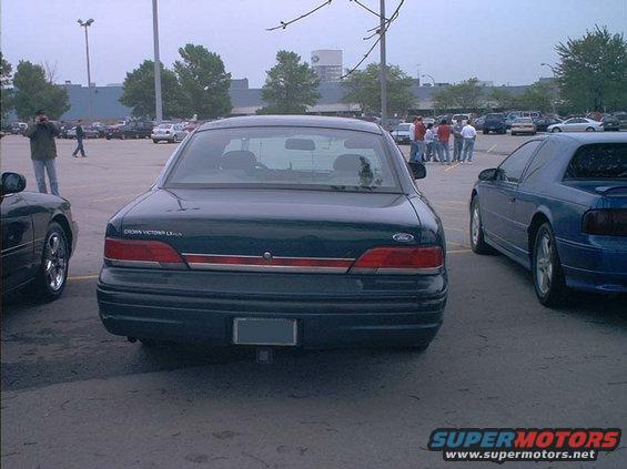 Dark green Ford Crown Victoria parked in a lot. Another blue car is to its right