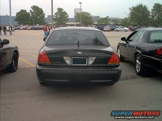 Rear view of a black Ford Crown Victoria parked in a lot. Another Crown Victoria is to the right