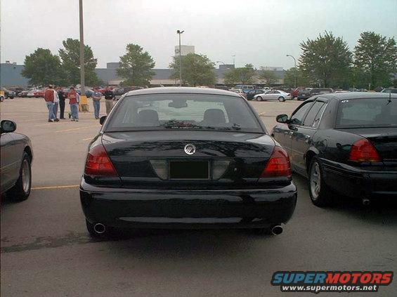Black sedan parked in a lot, rear view. Visible taillights, dual exhaust, and a Mercury emblem