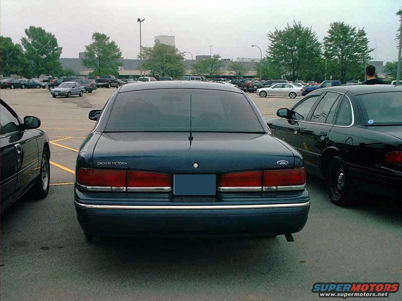 Dark blue Ford Crown Victoria parked in a lot, rear view. Another black Crown Victoria is to the right