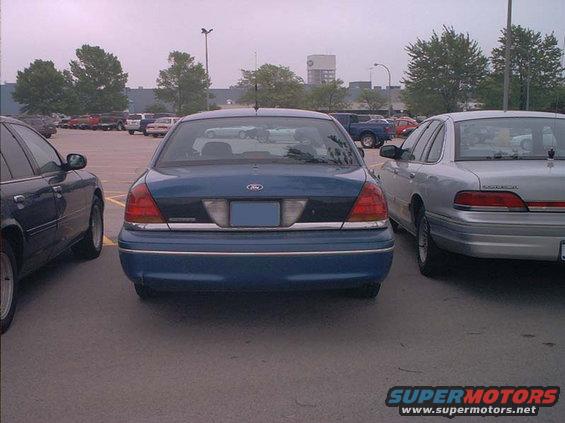 Blue Ford Crown Victoria parked in a lot next to a silver one. Rear view