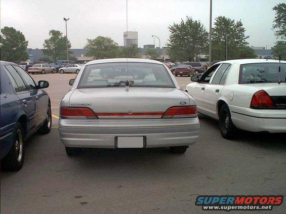 Silver 2000 Ford Crown Victoria parked between a blue sedan and a white police car