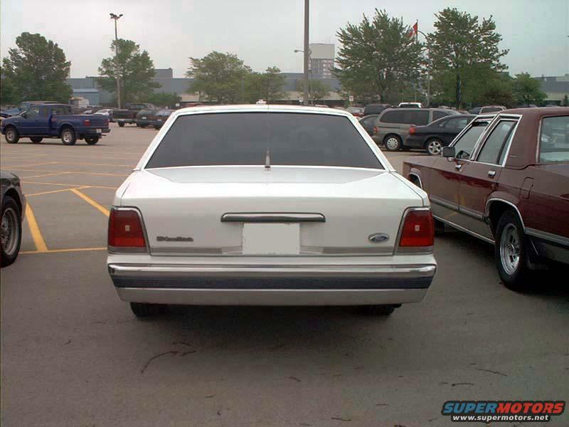 White 2000 Ford Crown Victoria, rear view, parked in lot. Chrome bumper, tinted windows