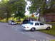 1998 Ford Crown Victoria - A white sheriff car is parked on the grass next to a road, with several other vehicles in the background.