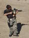 2005 Ford F-150 - A young person aims a rifle equipped with a drum magazine and optic at a shooting range.