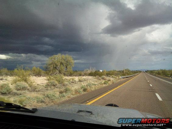 2004 Jeep Wrangler hood and windshield view on a highway with stormy clouds