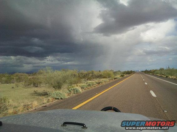 Desert road with storm clouds overhead, view from inside a vehicle