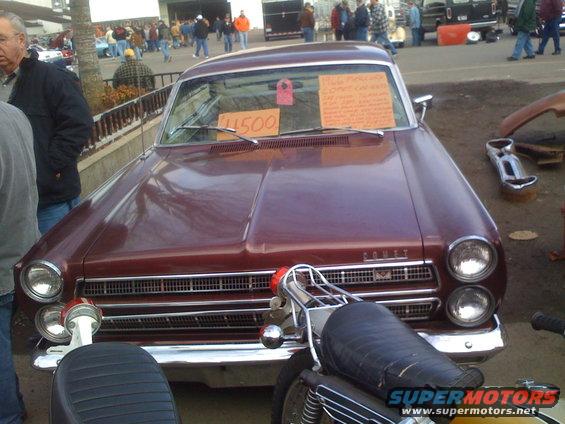 Maroon sedan with 'Comet' badge, parked next to a motorcycle. Price tag on windshield reads $1500