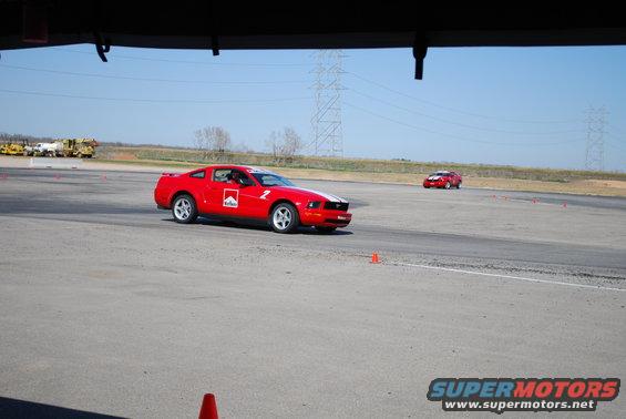 Red Ford Mustang with Marlboro decals and racing stripes on a track, another red car in the background
