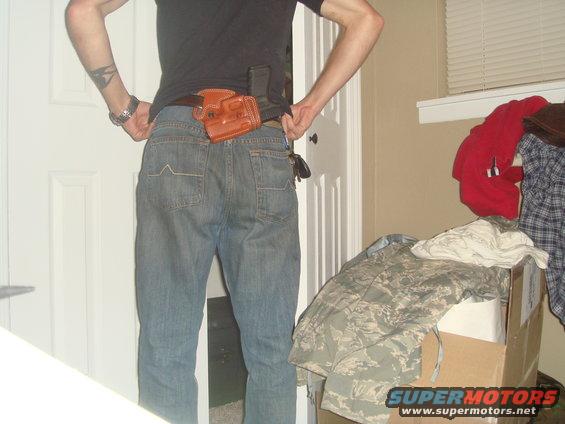 Person from behind wearing jeans and a leather holster with a gun inside