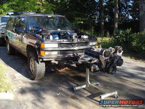 1995 Chevrolet Suburban with hood open and engine on stand in front