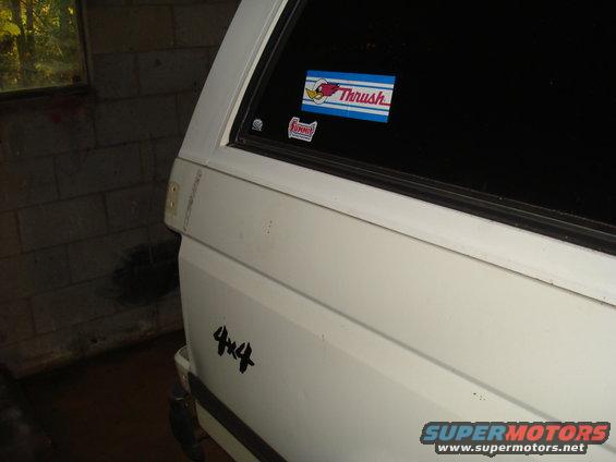 White SUV side view, showing a '4x4' decal and 'Thrush' and 'Funny' stickers on the rear window