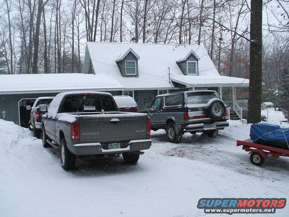 Gray and blue Ford Bronco with a spare tire on the back, parked in snow