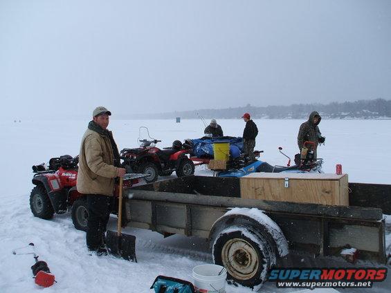 Trailer loaded with gear and four-wheelers on a frozen lake with people