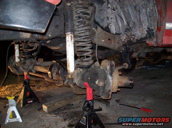 Vehicle's rear axle and suspension components are supported by jack stands for repair