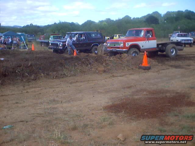 1976 Ford F-100 chassis stuck in mud, front 3/4 view, red and white cab