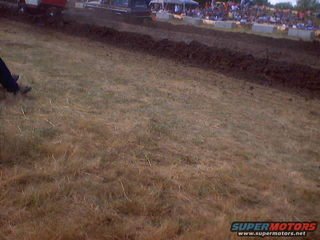 Trucks in a mud drag race with spectators in the background