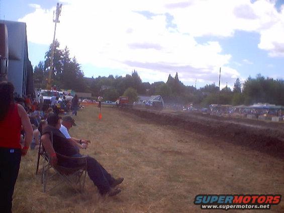 Mud drag racing event with spectators and vehicles on a dirt track