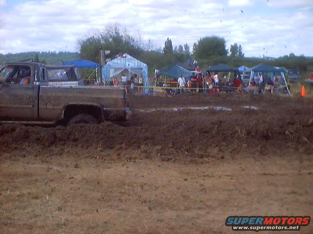 Muddy pickup truck stuck in mud at an outdoor event