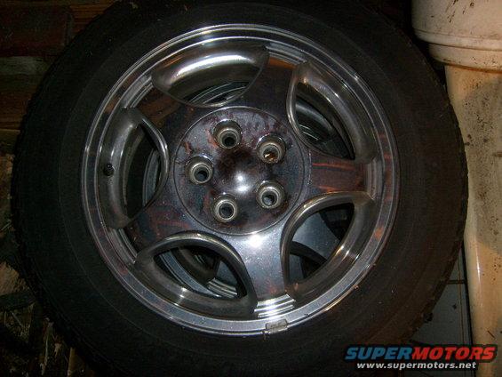Chrome wheel with five lug nut holes and a black tire