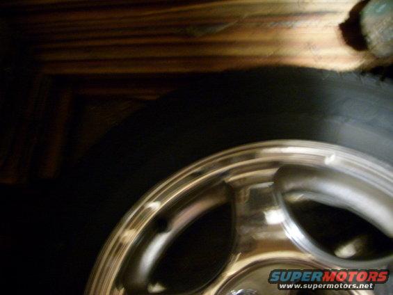 Chrome alloy wheel with five spokes and a black tire, partially visible