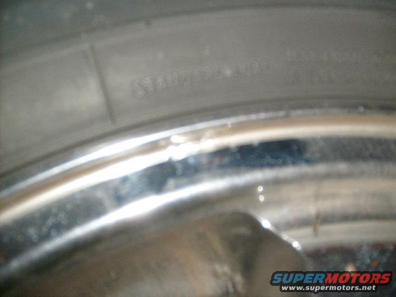 Close-up of tire sidewall with text and a chrome wheel rim