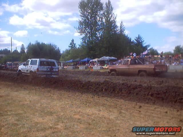Brown pickup truck and white SUV in mud race